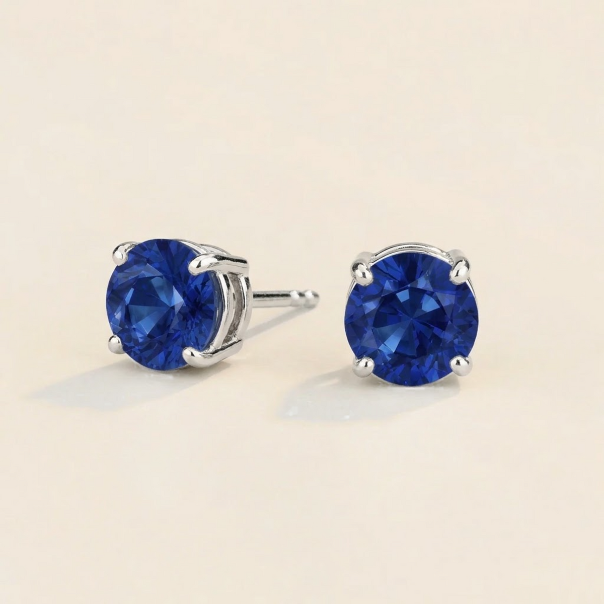 Nina round lab-grown blue sapphire solitaire stud earrings in white gold – angled view | Juvetti London