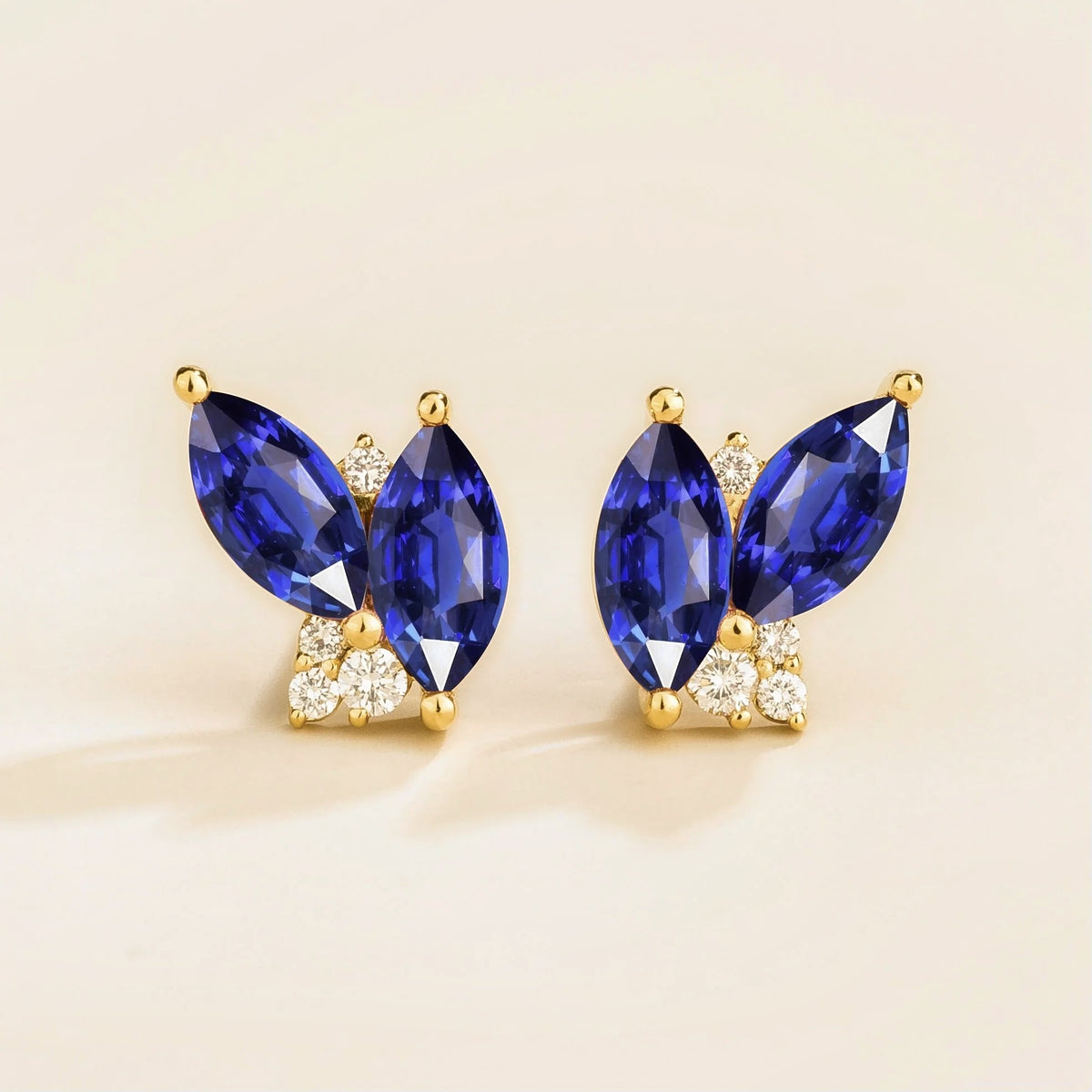 A pair of gold earrings with marquise blue sapphire and diamond accents.