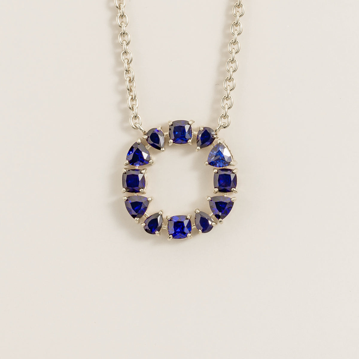 Glorie blue sapphire open circle pendant necklace in white gold, mixed-cut lab-grown sapphires, front view | Juvetti London