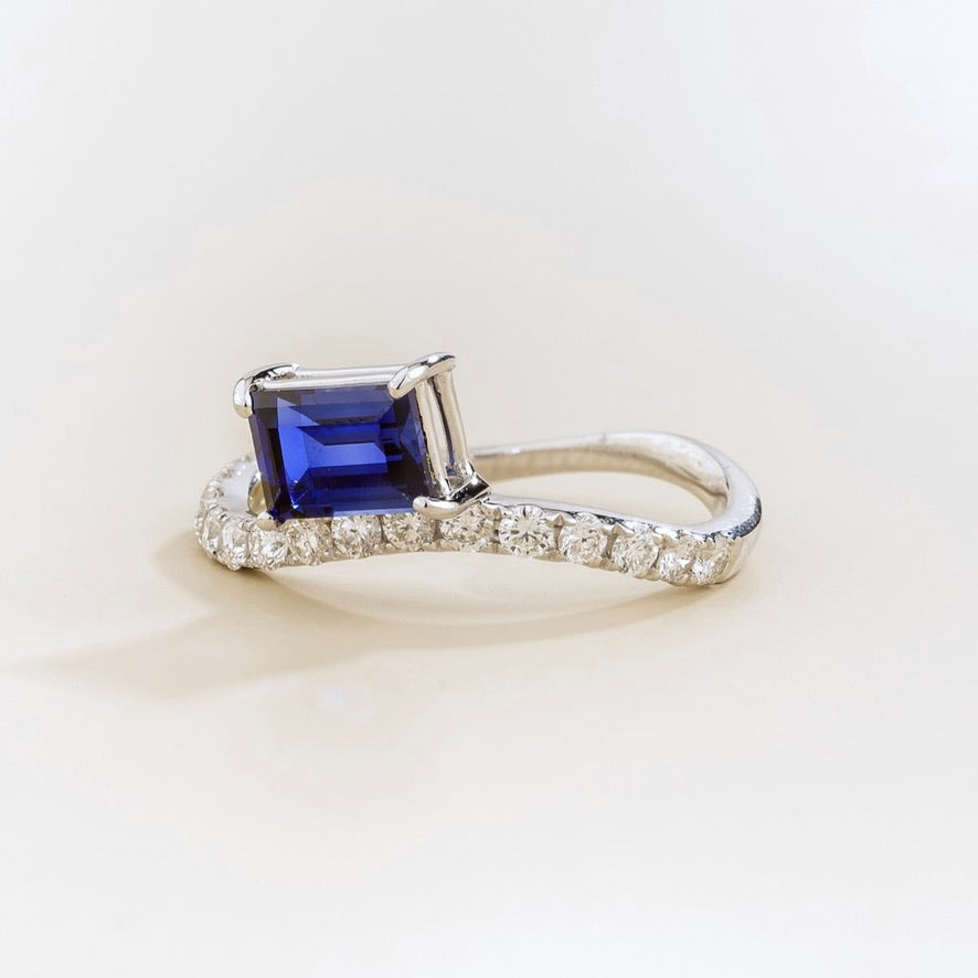 Luno blue sapphire emerald-cut ring with diamond pavé in white gold, lab-grown sapphire set east-west, angled view | Juvetti London