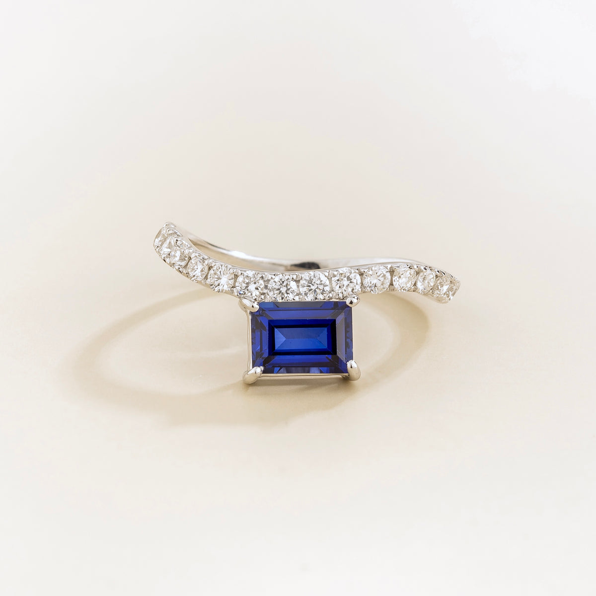 Luno blue sapphire emerald-cut ring with diamond pavé in white gold, lab-grown sapphire set east-west, side view | Juvetti London