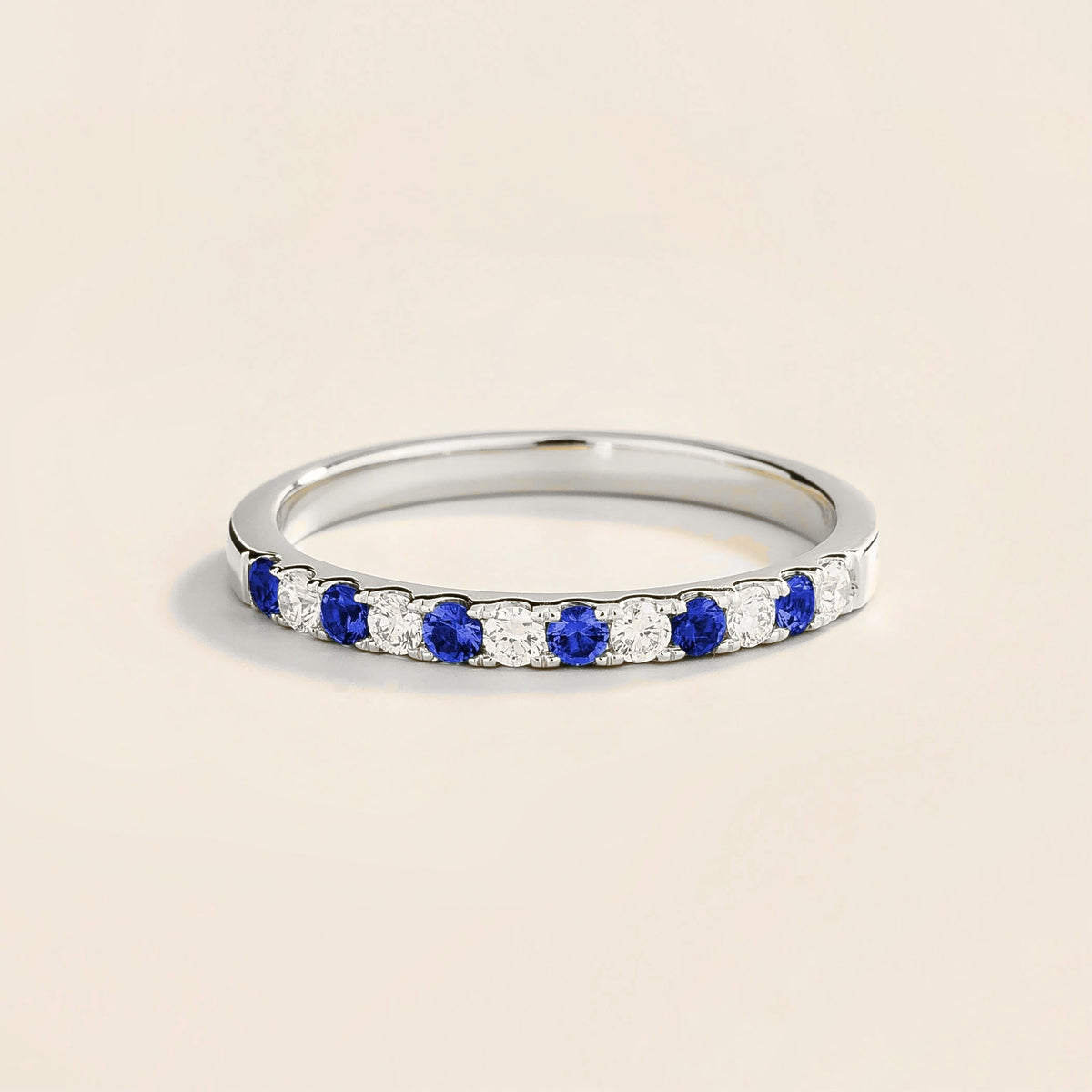A Salto white gold half eternity ring featuring alternating blue sapphire and diamond elements along its circumference.