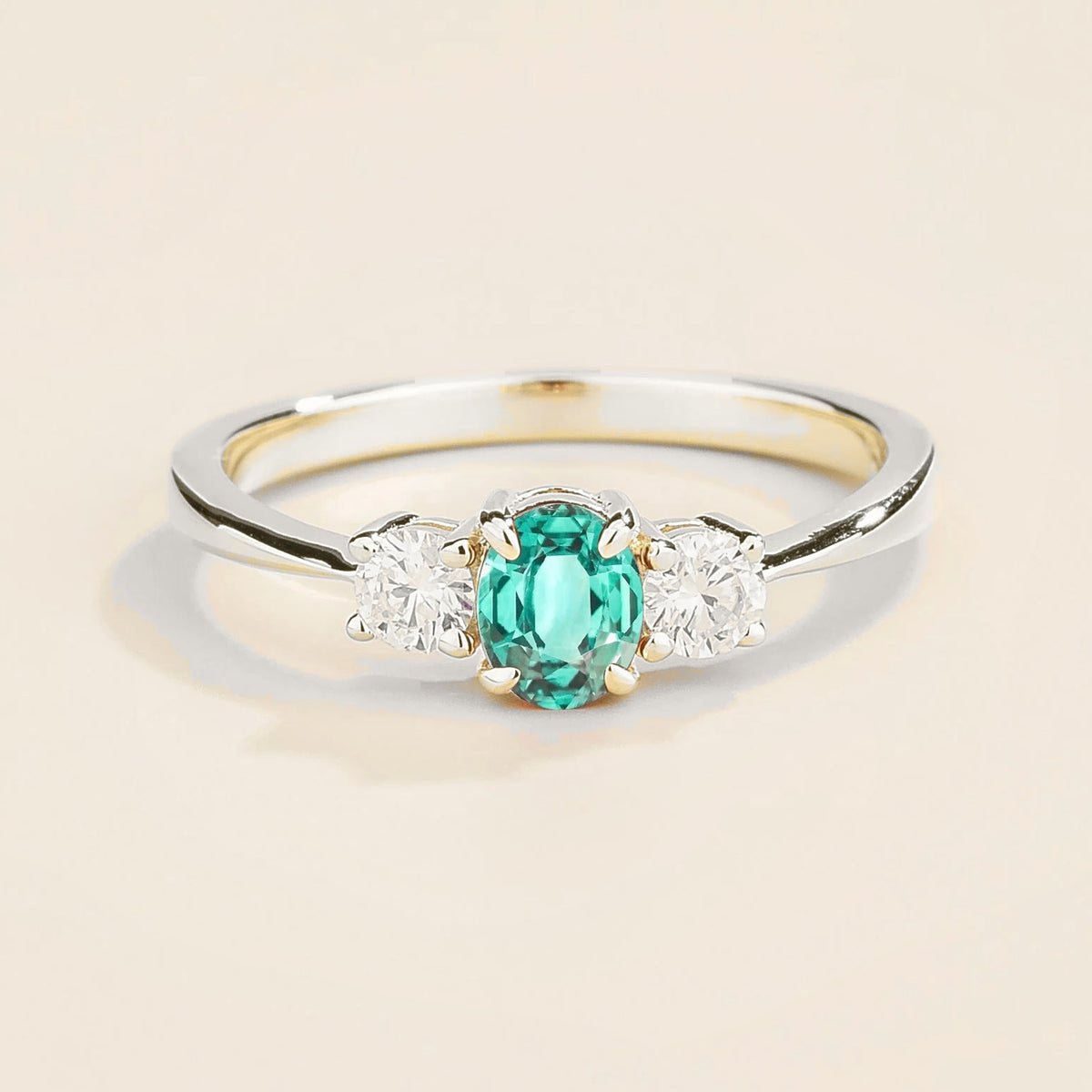 A white gold 3 gemstone ring featuring a central Paraiba with flanking diamonds, viewed from the front against a plain background.