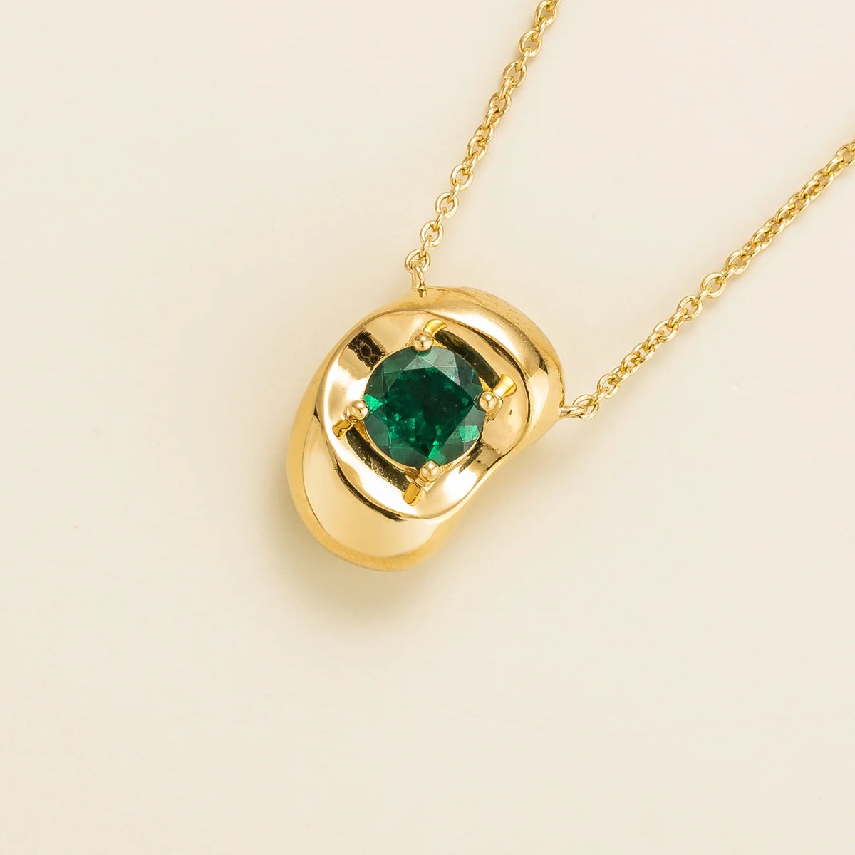 Fava round lab-grown emerald pendant necklace in gold, sculpted pebble setting, angled view | Juvetti London