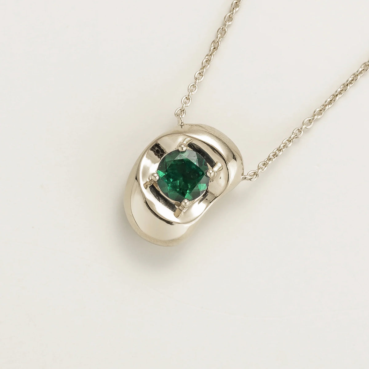 Fava round lab-grown emerald pendant necklace in white gold, sculpted pebble setting, angled view | Juvetti London