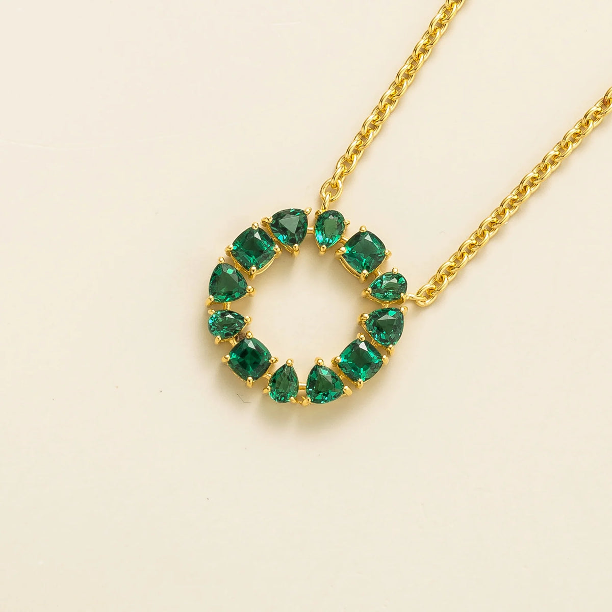 Glorie emerald open circle pendant necklace in gold, mixed-cut lab-grown emeralds, angled view | Juvetti London