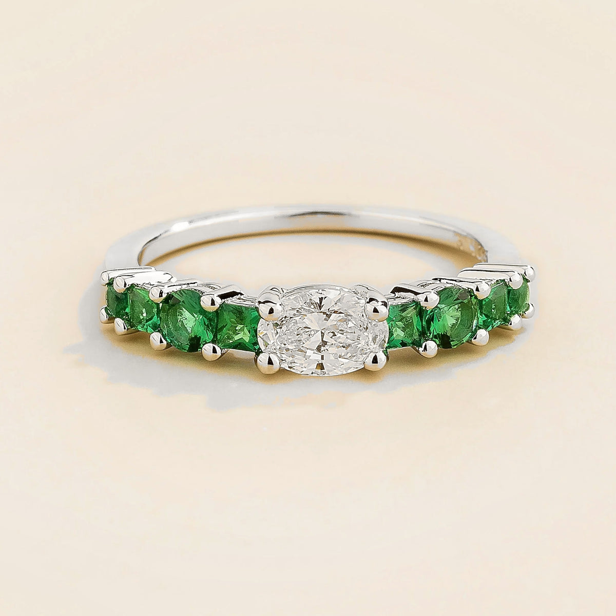 Petra oval diamond & emerald half eternity ring in white gold