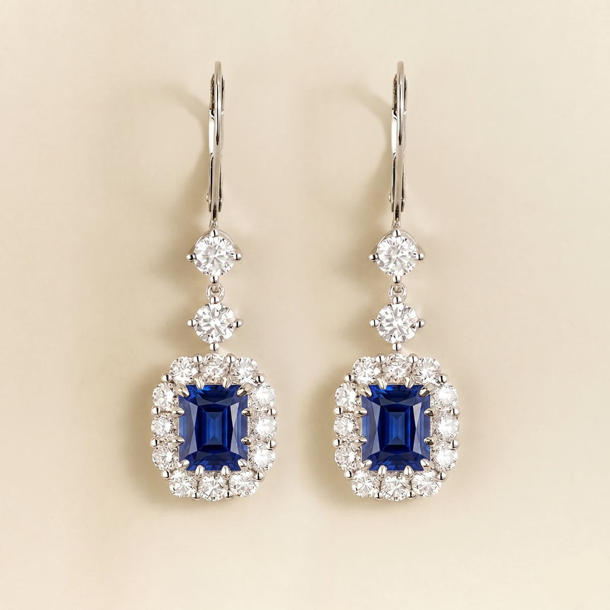 Pippa emerald-cut blue sapphire and diamond halo drop earrings in white gold, lab-grown sapphires hanging from round diamonds on lever-back hooks