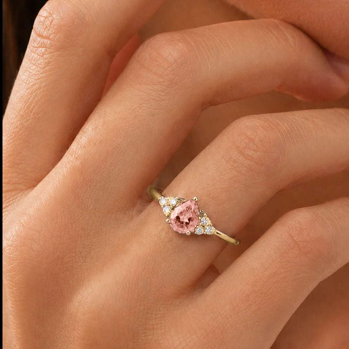 Hand wearing a pear-cut lab-grown morganite and diamond ring in gold | Pisa by Juvetti