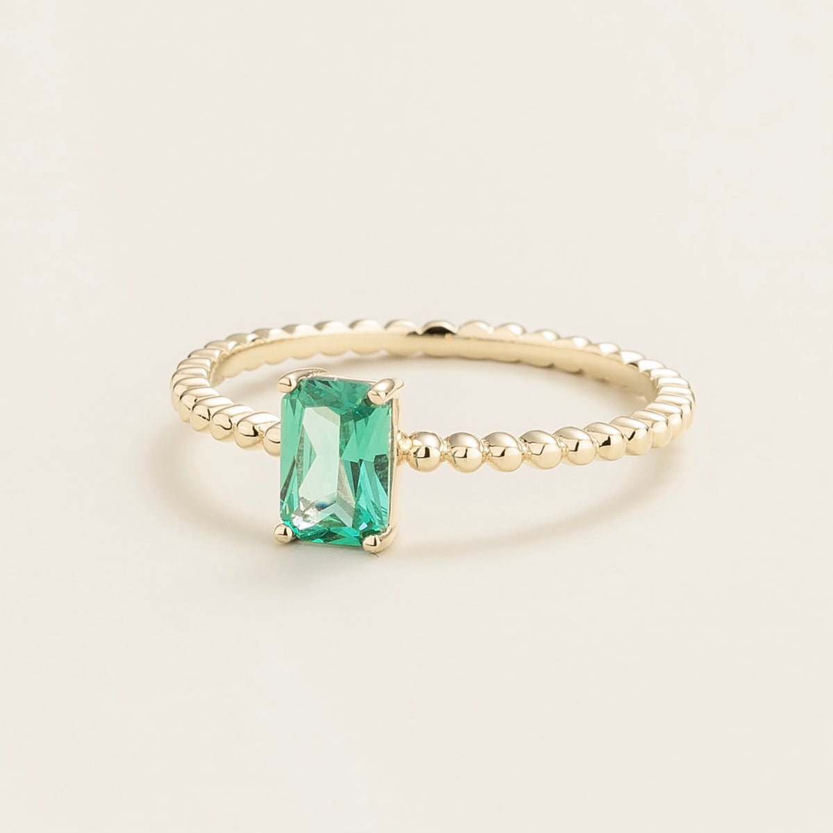 Fondi emerald-cut lab-grown Paraiba sapphire beaded band ring in gold – angle view | Juvetti London