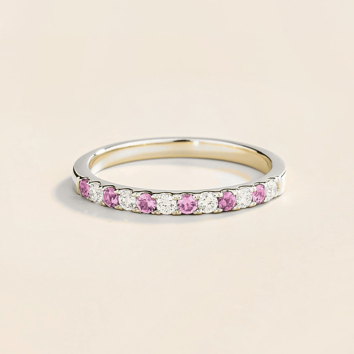A white gold half eternity ring with pastel pink sapphire and diamonds set in an alternating pattern.