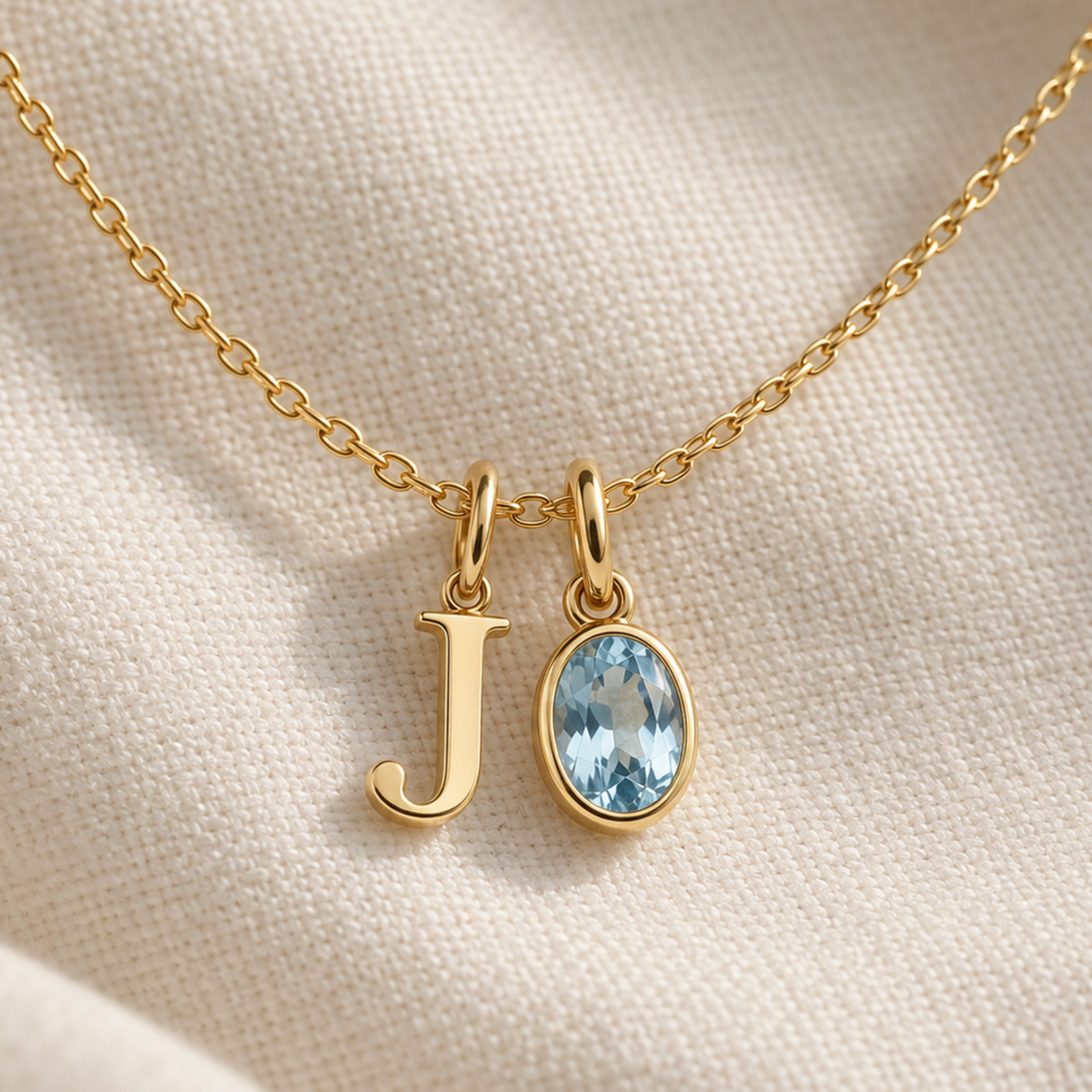 Personalised initial and gemstone charm necklace in gold, letter J charm and bezel-set oval aquamarine charm