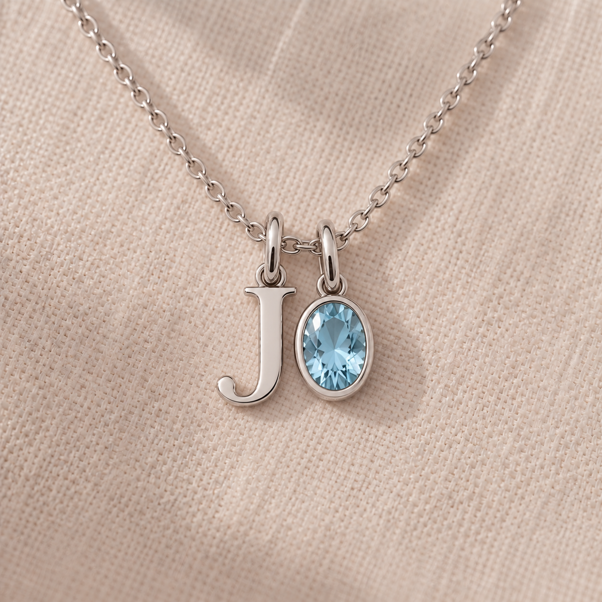 Personalised initial and gemstone charm necklace in white gold, letter J charm and bezel-set oval aquamarine charm