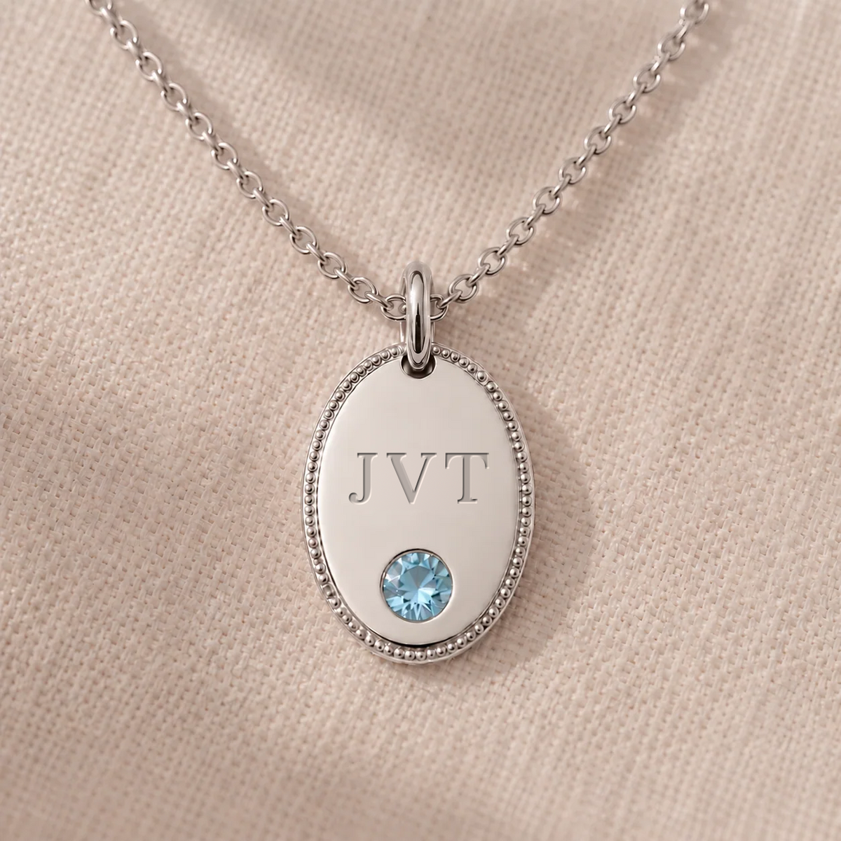 Personalised initial oval pendant necklace in white gold, engraved JVT with flush-set aquamarine and milgrain border