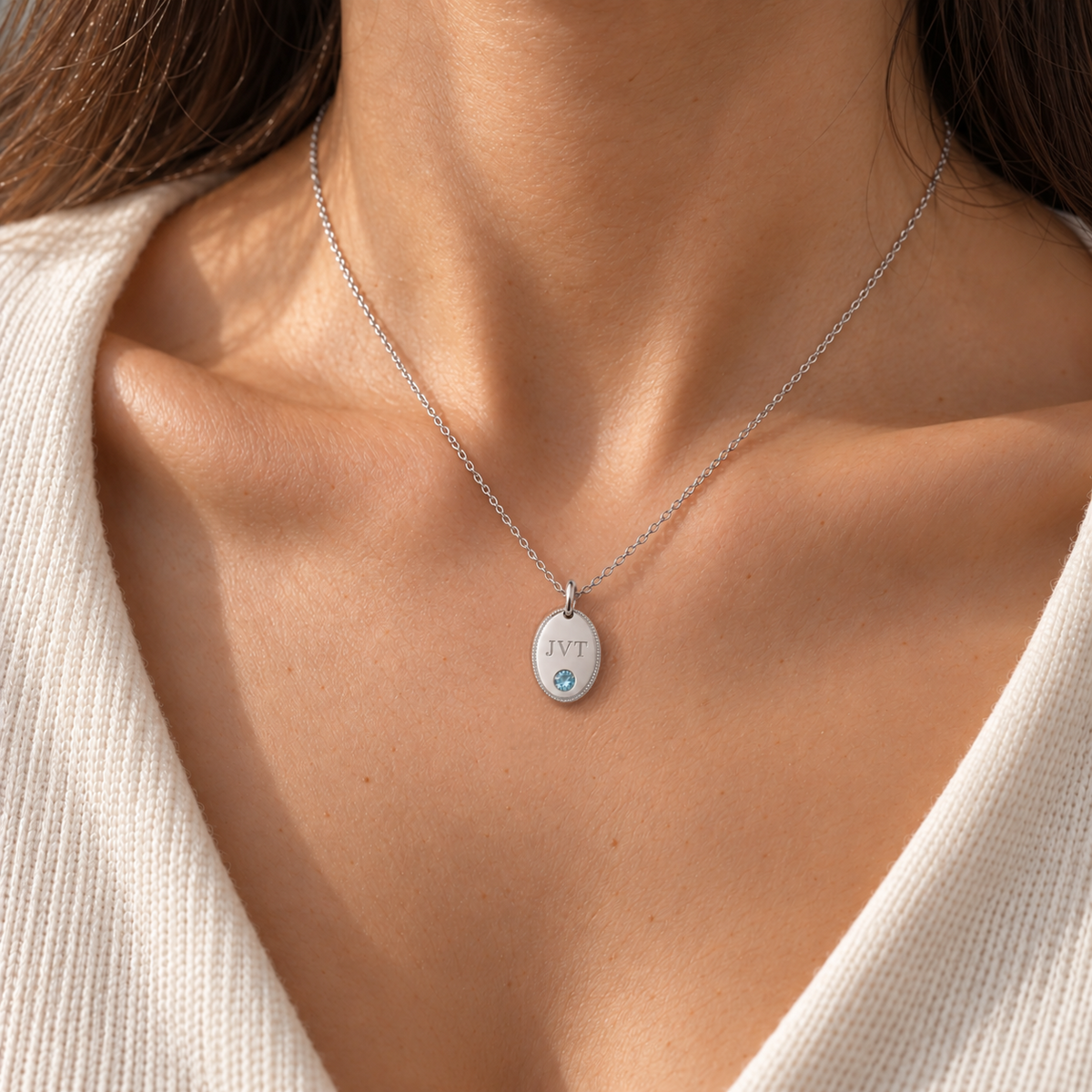 Personalised initial oval pendant necklace in white gold worn on model, shown at true size