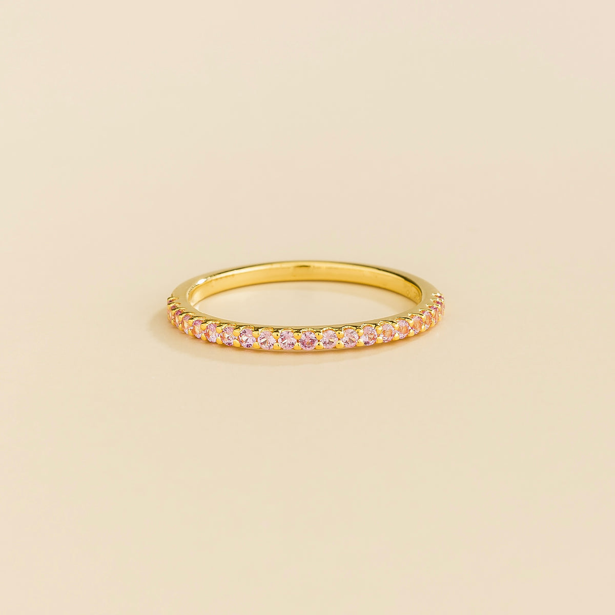 Juvetti yellow gold half eternity band set with round lab-grown pink sapphires.