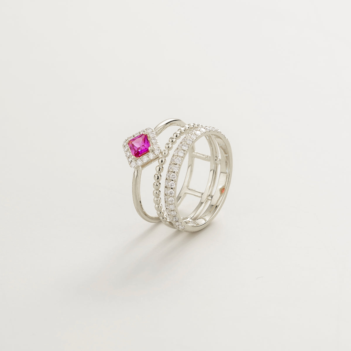 Amici triple-band stacking ring in white gold, princess-cut lab-grown pink sapphire in a diamond halo with beaded and pavé bands, side view | Juvetti London