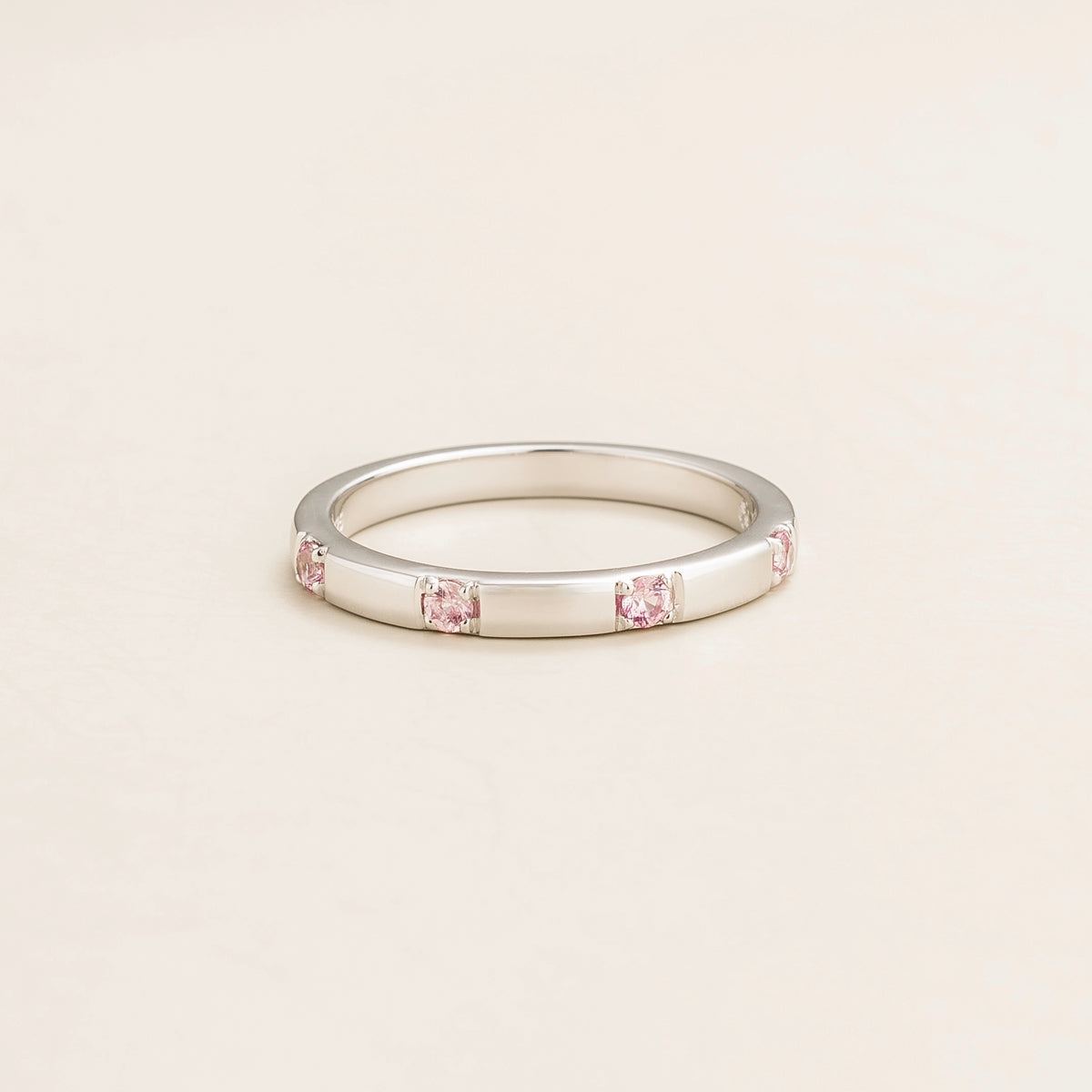 Juvetti white gold band set with round lab-grown pink sapphires in a sleek modern design.