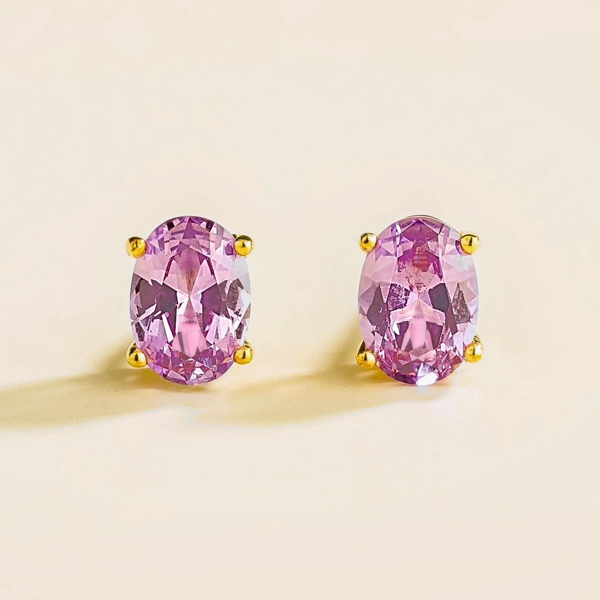 A pair of Ovo gold earrings set with oval Purple sapphires.