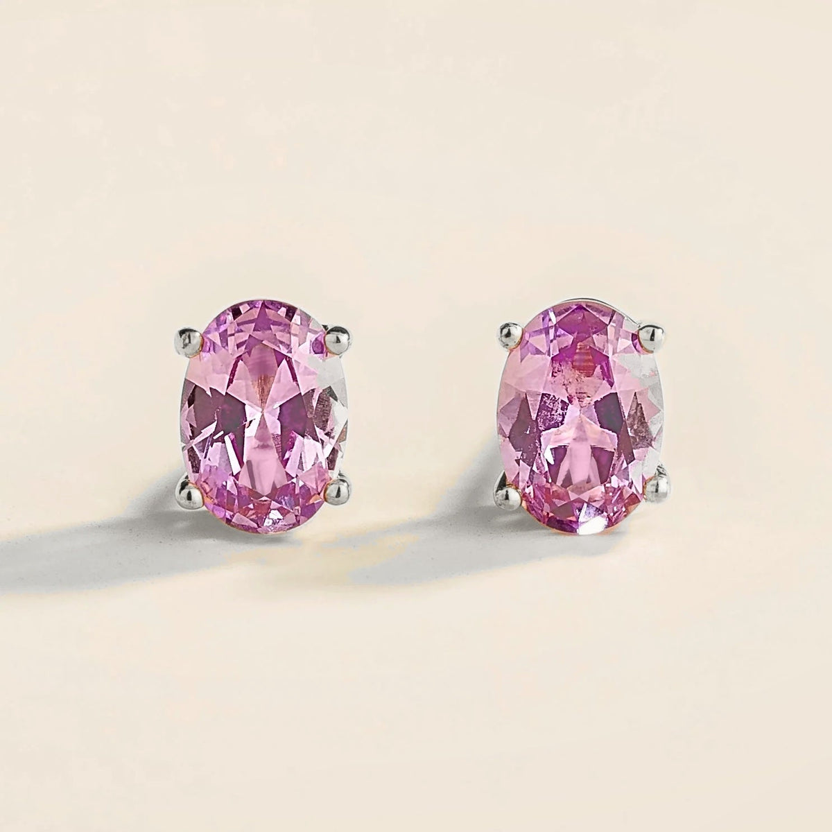 A pair of white gold solitaire stud earrings set with oval-shaped purple sapphires.