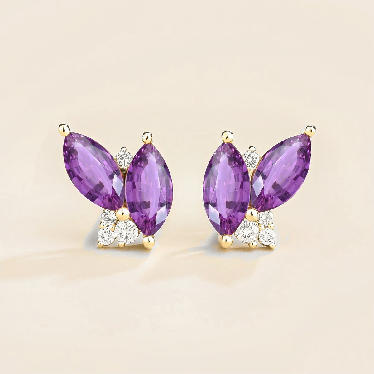A pair of white gold earrings with marquise purple sapphire and diamond, butterfly shaped settings.