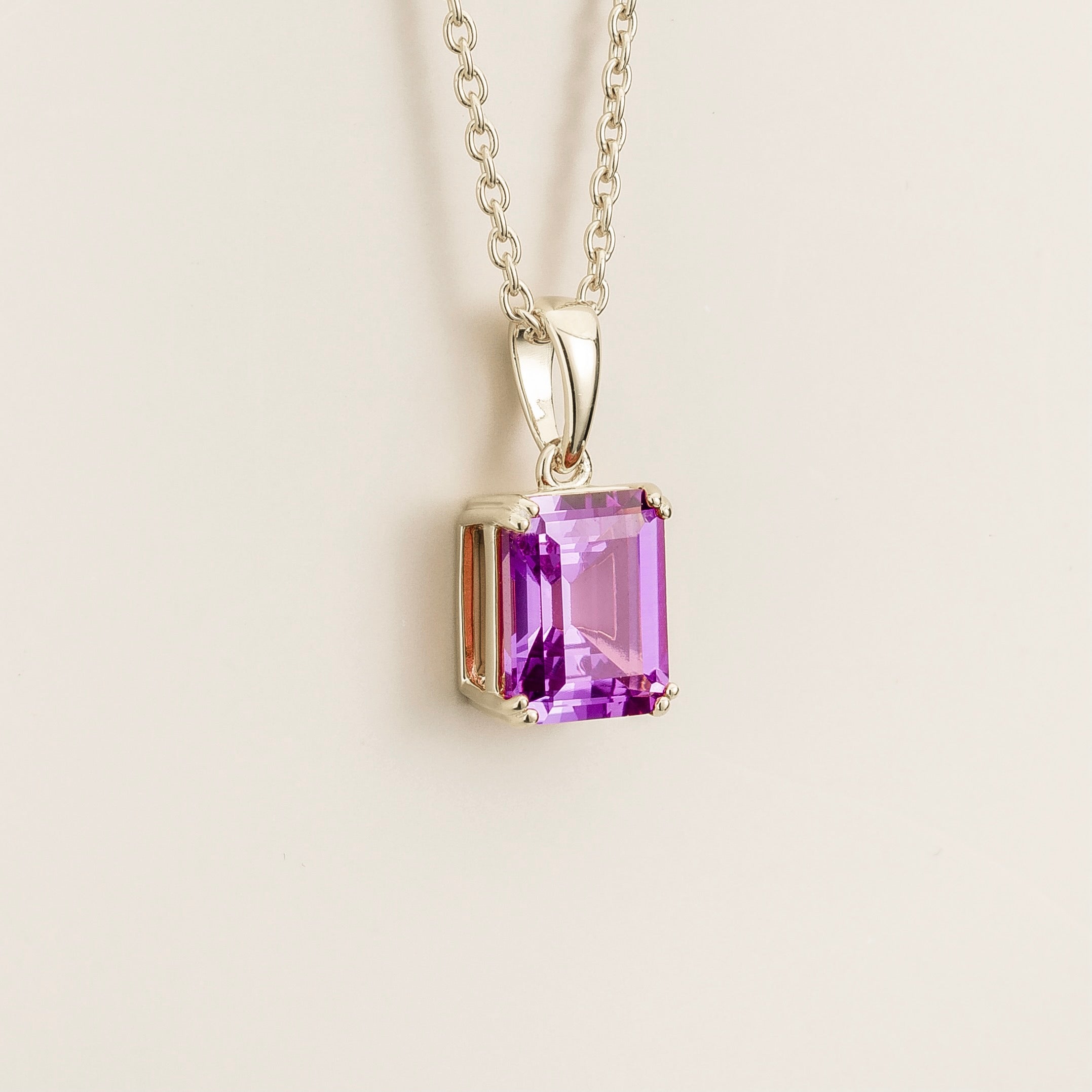 Angled view of the Thamani purple sapphire necklace in white gold showing the emerald cut purple sapphire, Juvetti London
