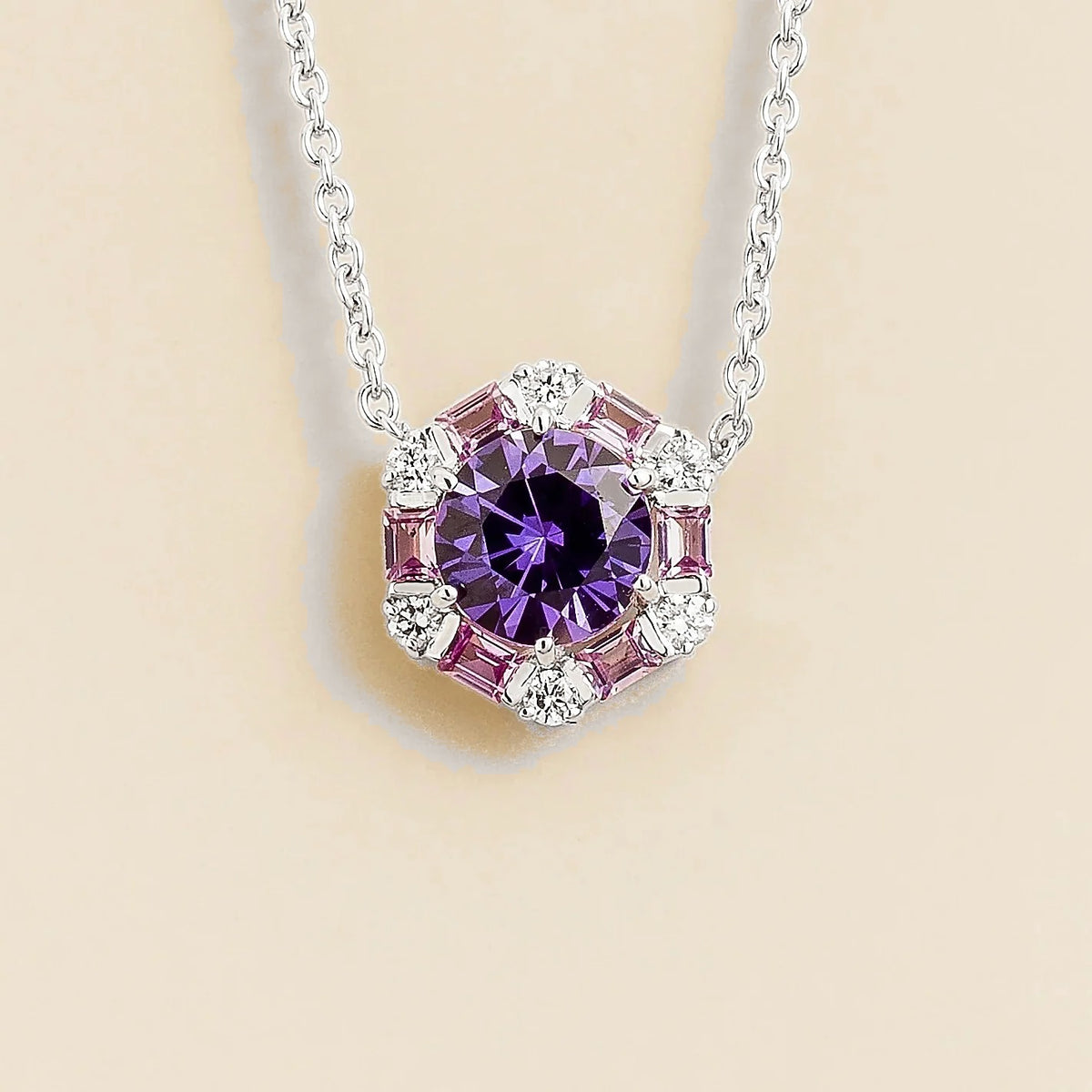 Hexagon necklace with round purple sapphire gemstone with pink sapphire and diamond halo on a beige background