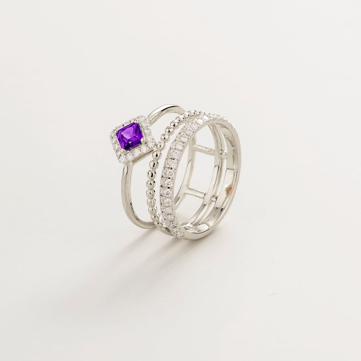 Amici triple-band stacking ring in white gold, princess-cut lab-grown purple sapphire in a diamond halo with beaded and pavé bands, side view | Juvetti London
