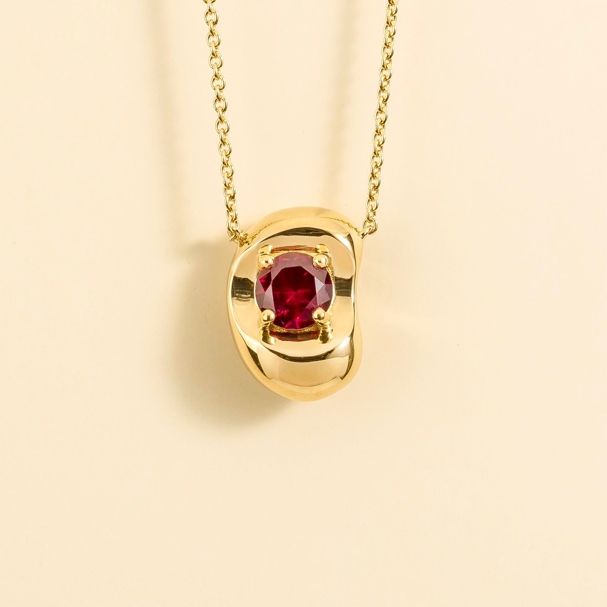 Front view of the Fava Round Ruby Oval Solitaire Pendant Necklace in Gold, handcrafted by Juvetti London
