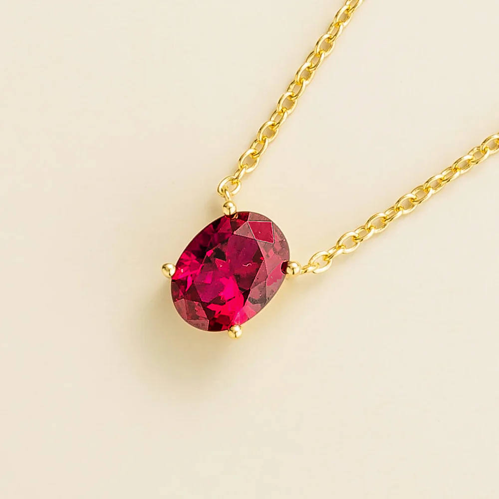 Angled view of the Ovo ruby necklace in gold showing the oval ruby, Juvetti London