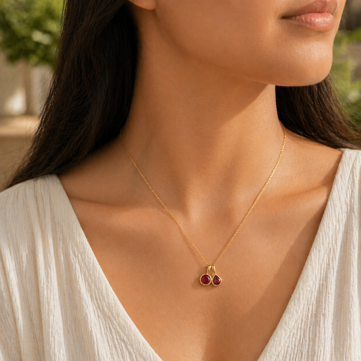 Angled view of the Prunus ruby necklace in gold showing the round and pear ruby, Juvetti London