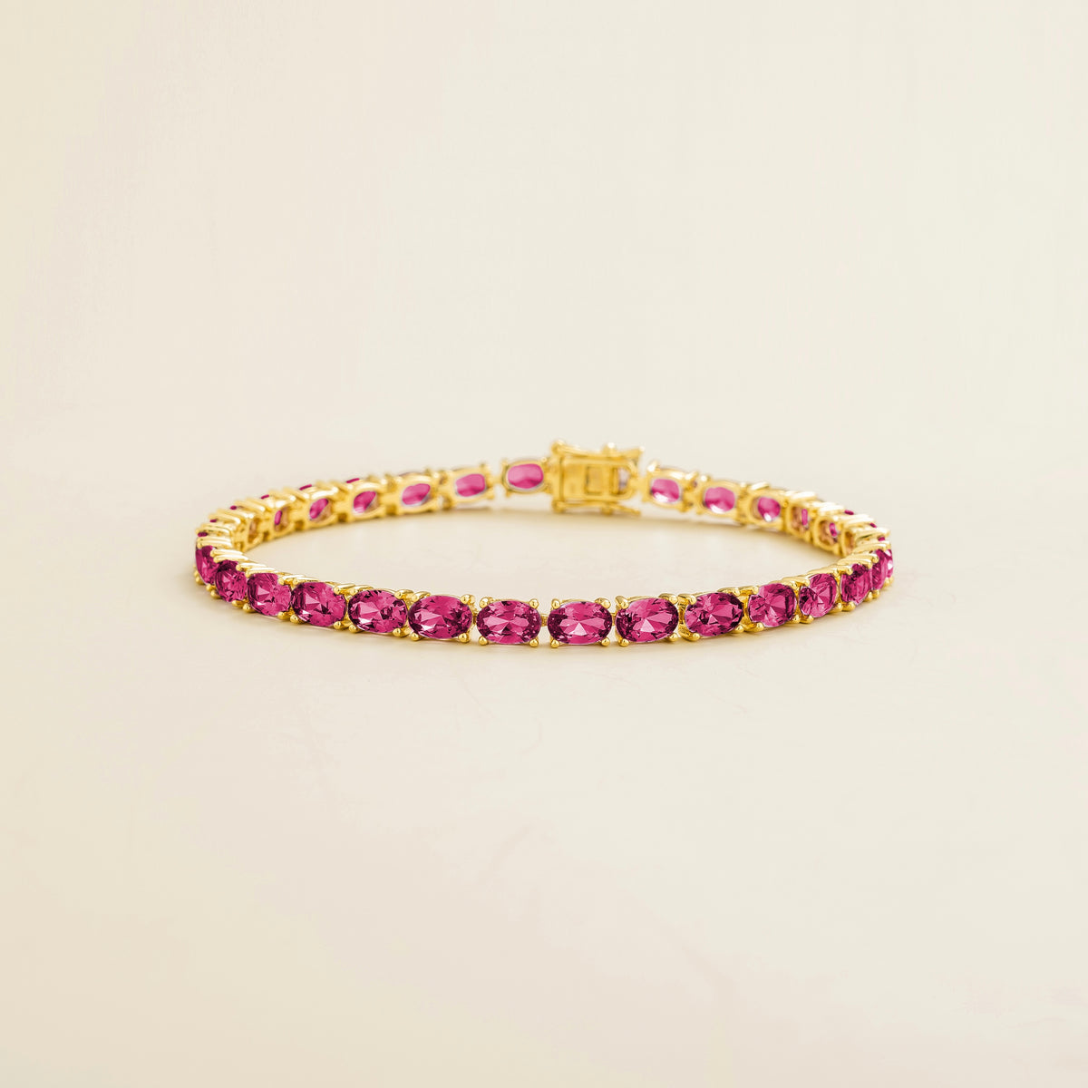 A tennis bracelet featuring yellow gold and vivid pink sapphire gemstones.