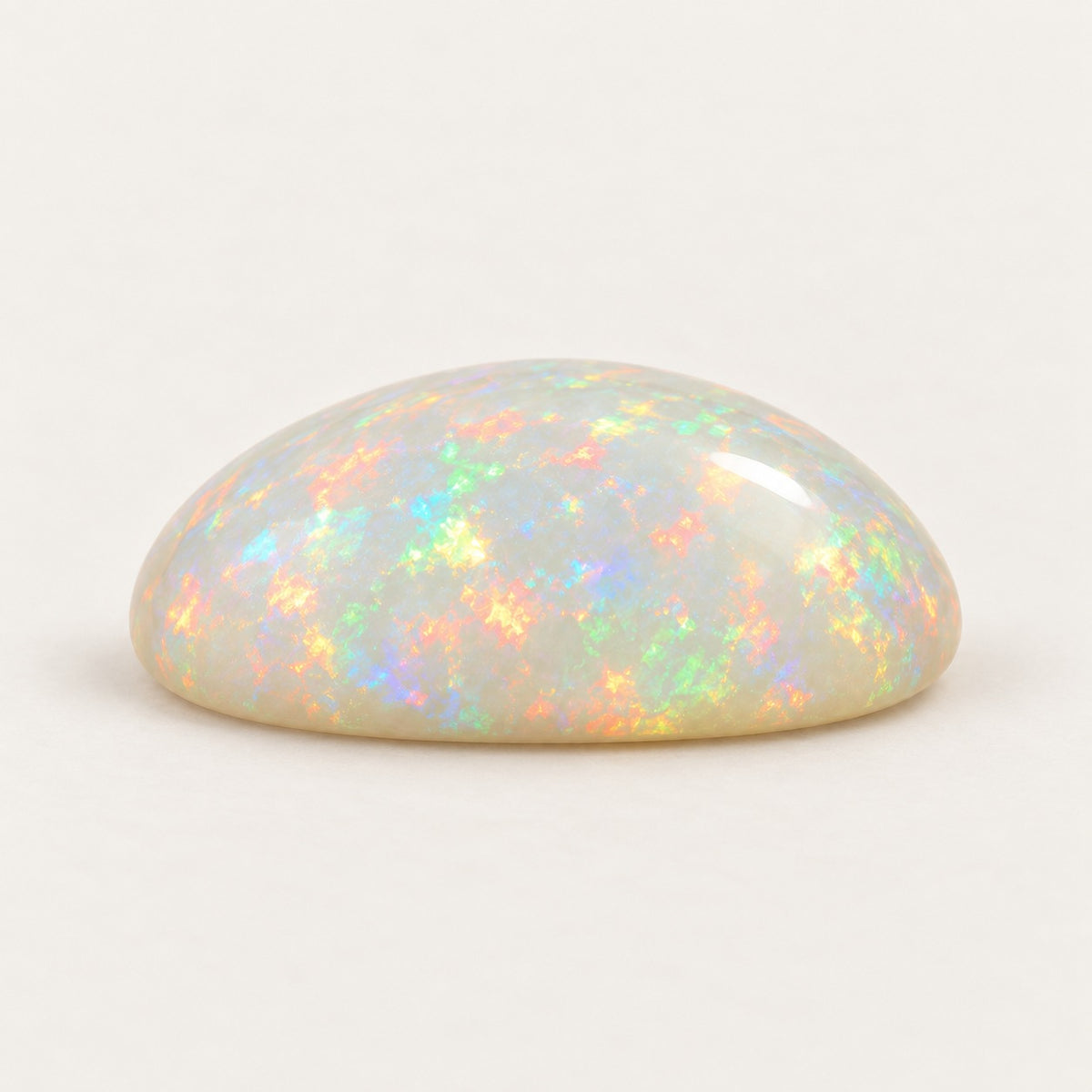 White lab-grown opal, oval cabochon, side view