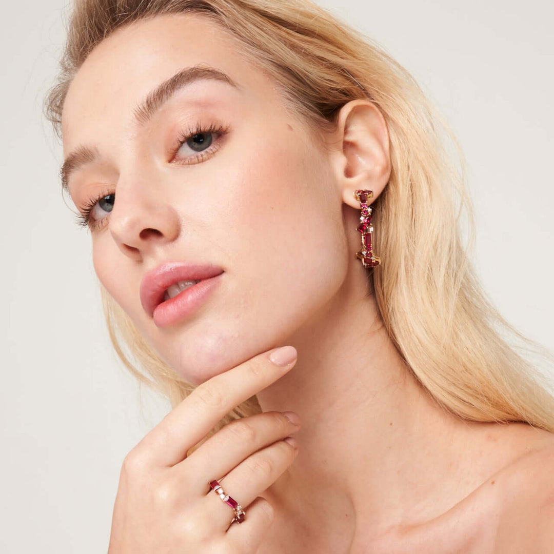 A model wearing Lanna large hoop earrings set with lab grown diamond and ruby gem stones. She also wears Forma ring set with lab grown ruby and diamond gem stones.